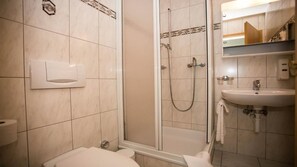 Un baño con inodoro, lavamanos, ducha y toallero.