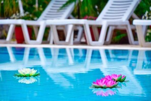 A swimming pool with two lotus flowers floating on the water, surrounded by white lounge chairs. - Villa Valia (Corfu)