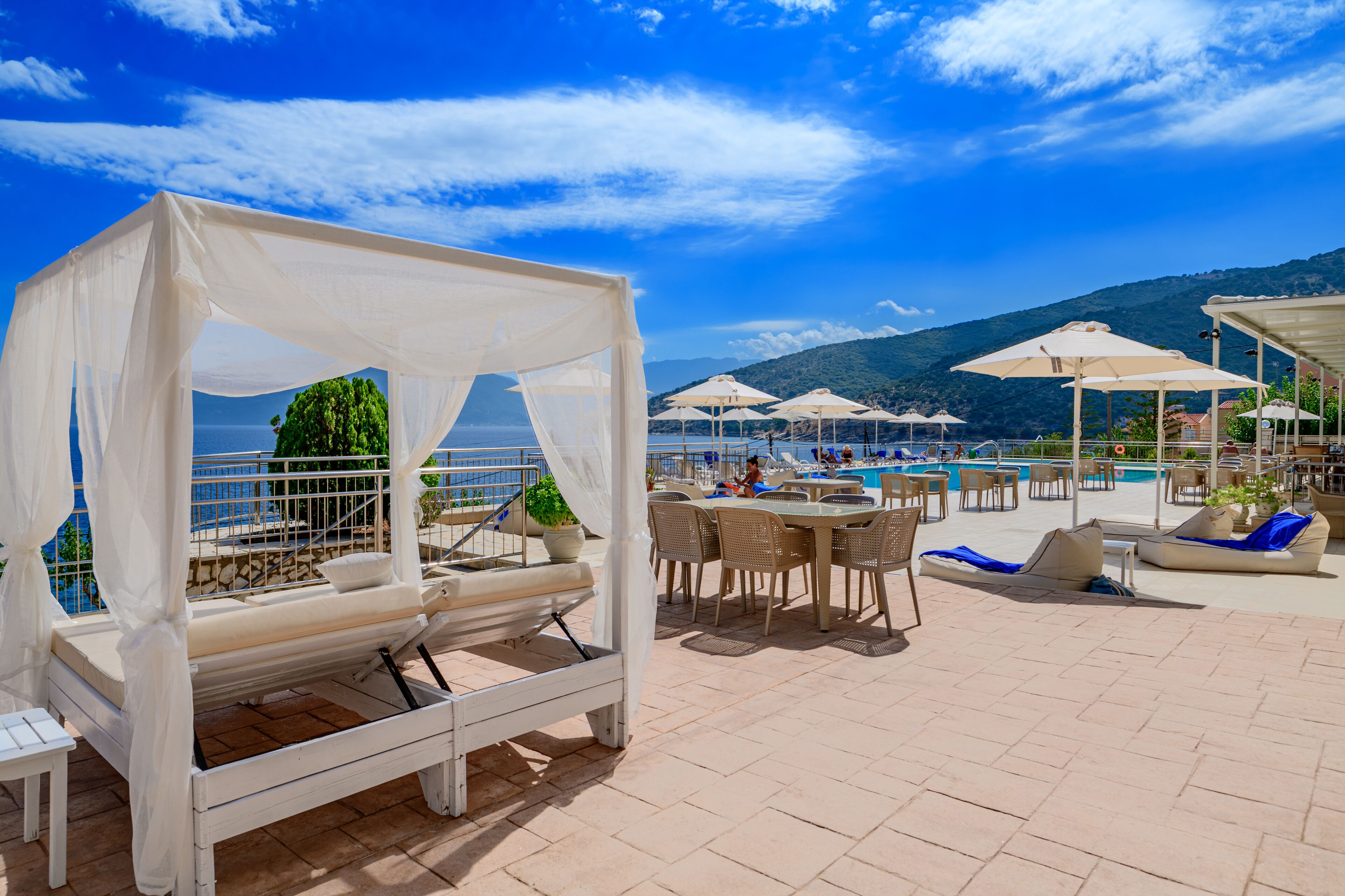 A rooftop terrace with a pool, lounge chairs, and umbrellas.