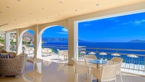 A spacious balcony with white wicker furniture and a view of the sea. - Odyssey Boutique Hotel (Kefalonia)