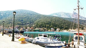 A marina with boats docked, a clear view of the water, and a backdrop of green hills. - Odyssey Boutique Hotel (Kefalonia)