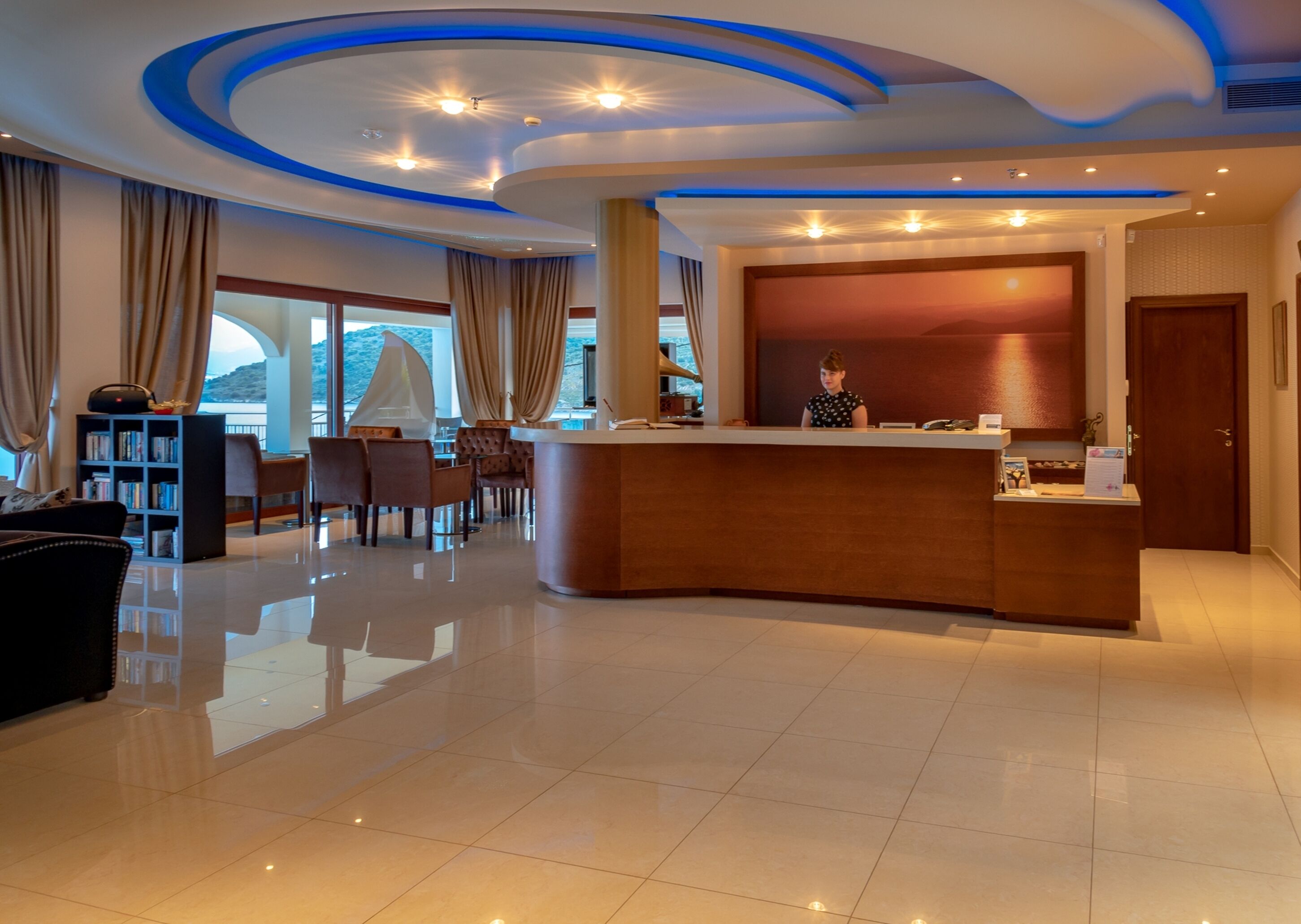 A hotel lobby with a reception desk, seating area, and a large window offering a view.