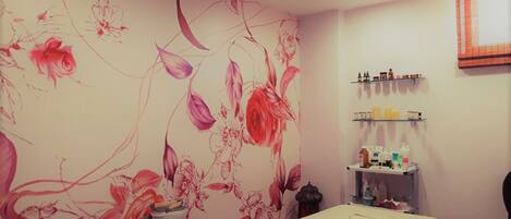 Una habitación con un mural floral, una mesa de recepción y estantes con diversos objetos.