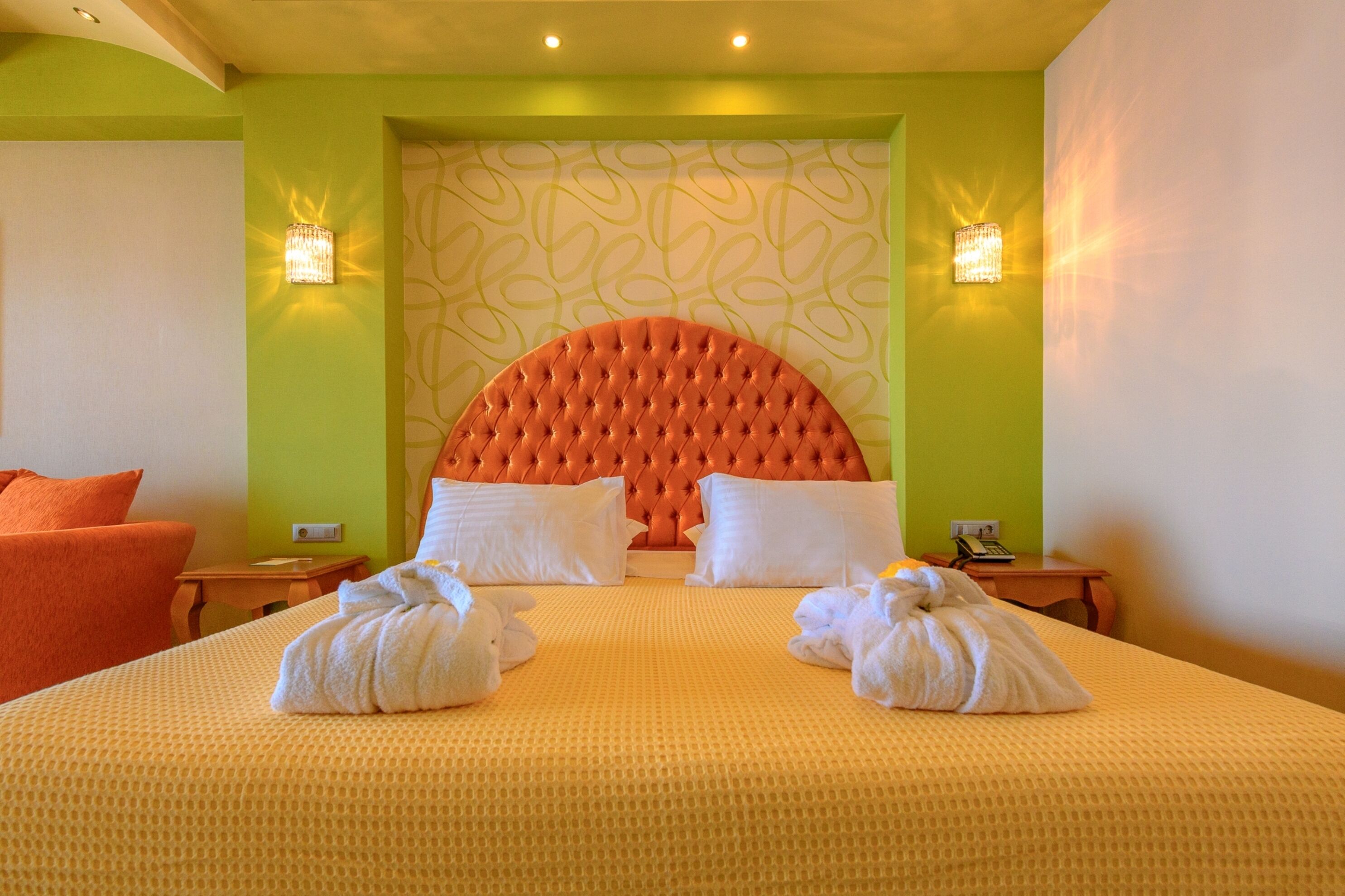 A hotel room with a large bed, two nightstands, a headboard, and two wall sconces.