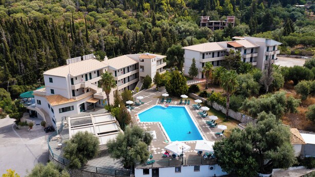 A resort with a swimming pool, multiple buildings, and surrounding greenery.