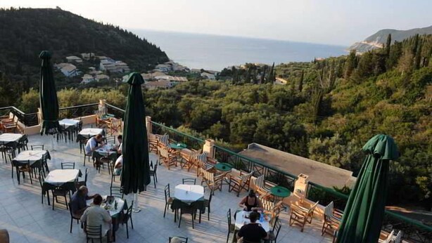 An outdoor terrace with tables and chairs, overlooking a coastal landscape with hills and the sea. - Santa Marina (Lefkada)