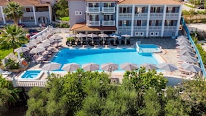 A resort with a large pool, multiple balconies, and a view of the surrounding hills. - Anamar Zante Hotel (Zakynthos)