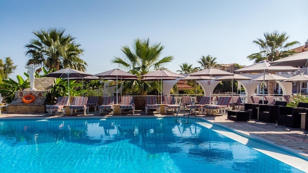 A pool area with lounge chairs and umbrellas, surrounded by palm trees. - Anamar Zante Hotel (Zakynthos)