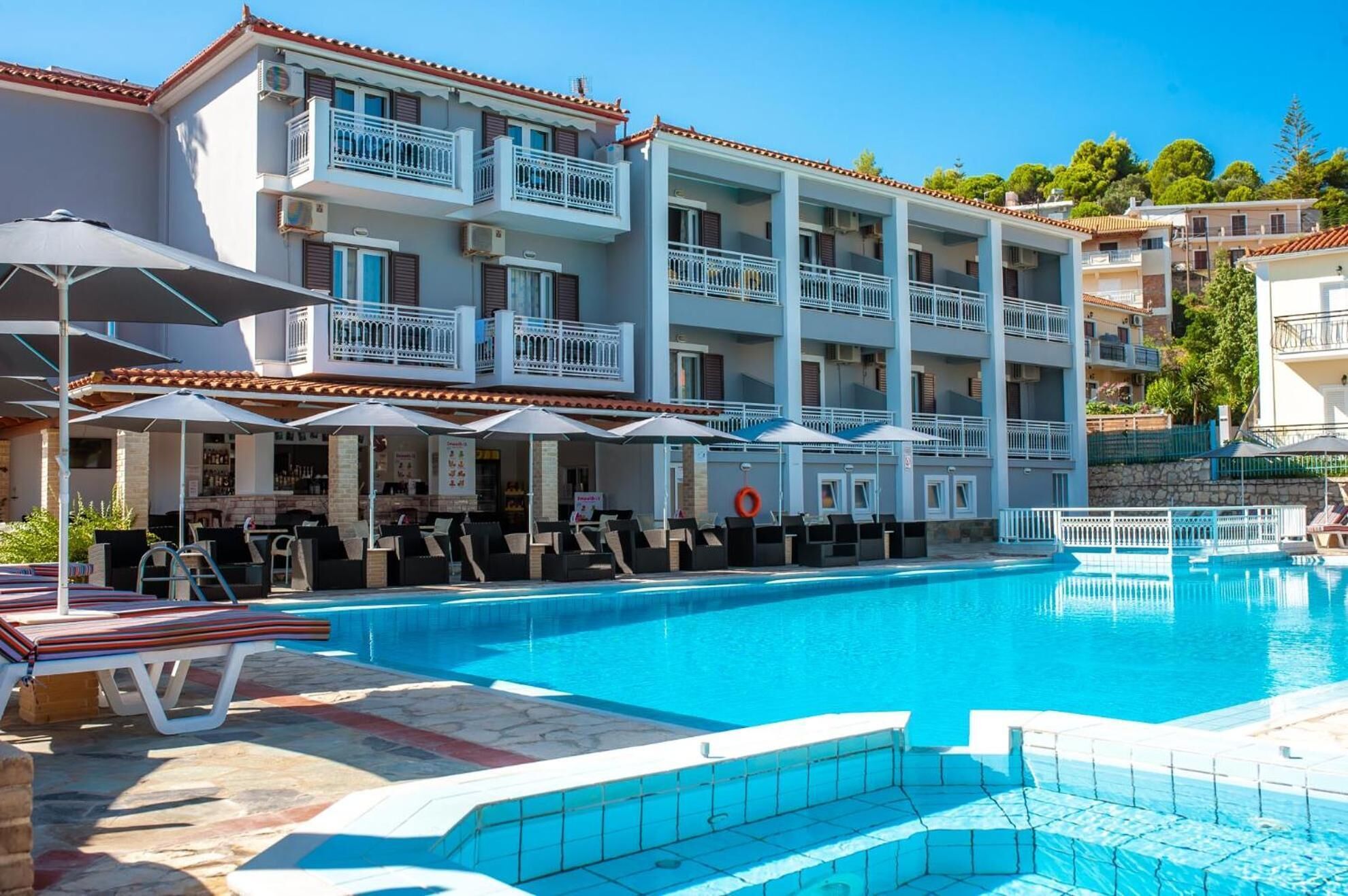 A hotel with a swimming pool, outdoor seating, and a bar area.