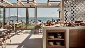 A coastal restaurant with wicker furniture, a wooden ceiling, and a view of the ocean. - Windmill Bay Hotel (Zakynthos)