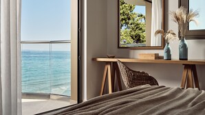 A bedroom with a view of the sea, a wooden desk, a wicker chair, and two vases on a shelf. - Windmill Bay Hotel (Zakynthos)