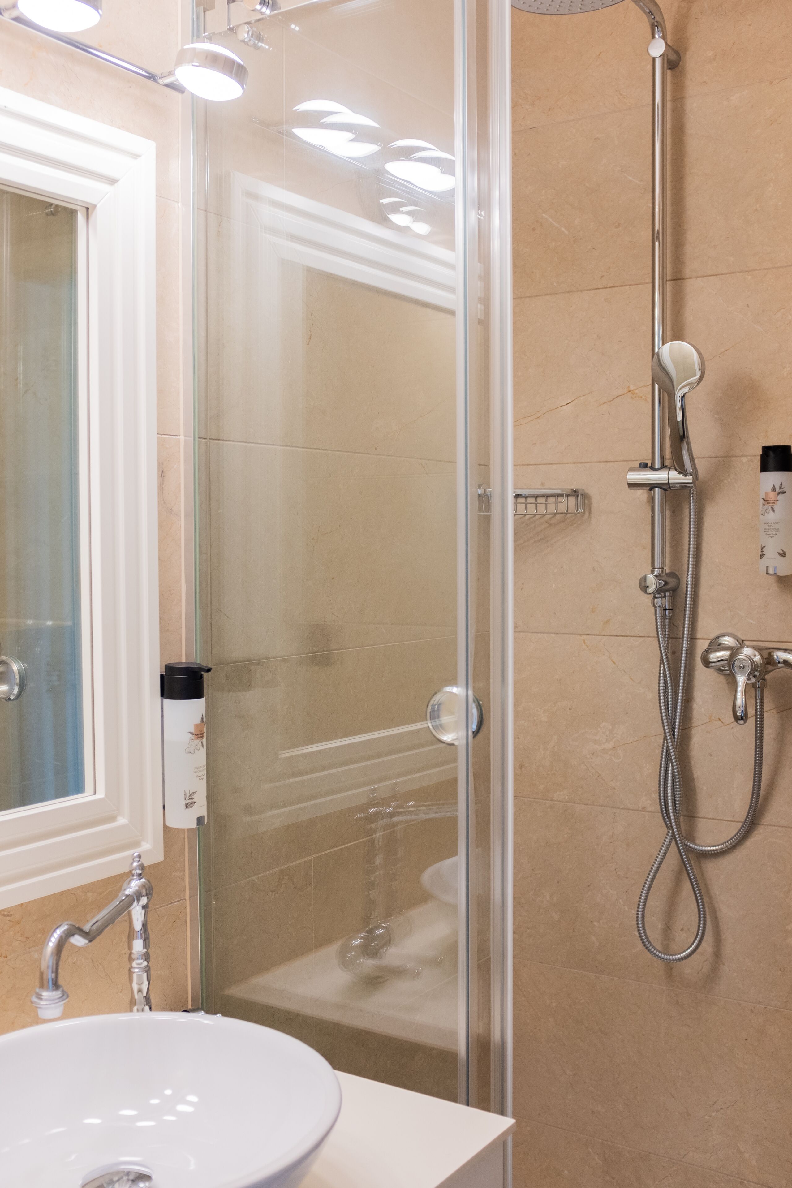 Un baño moderno con ducha de vidrio, lavabo blanco y cabezal de ducha de mano.