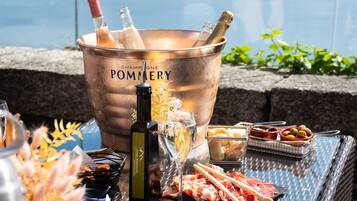 Un balde de champán con botellas y copas, diversos aperitivos y vistas al agua.