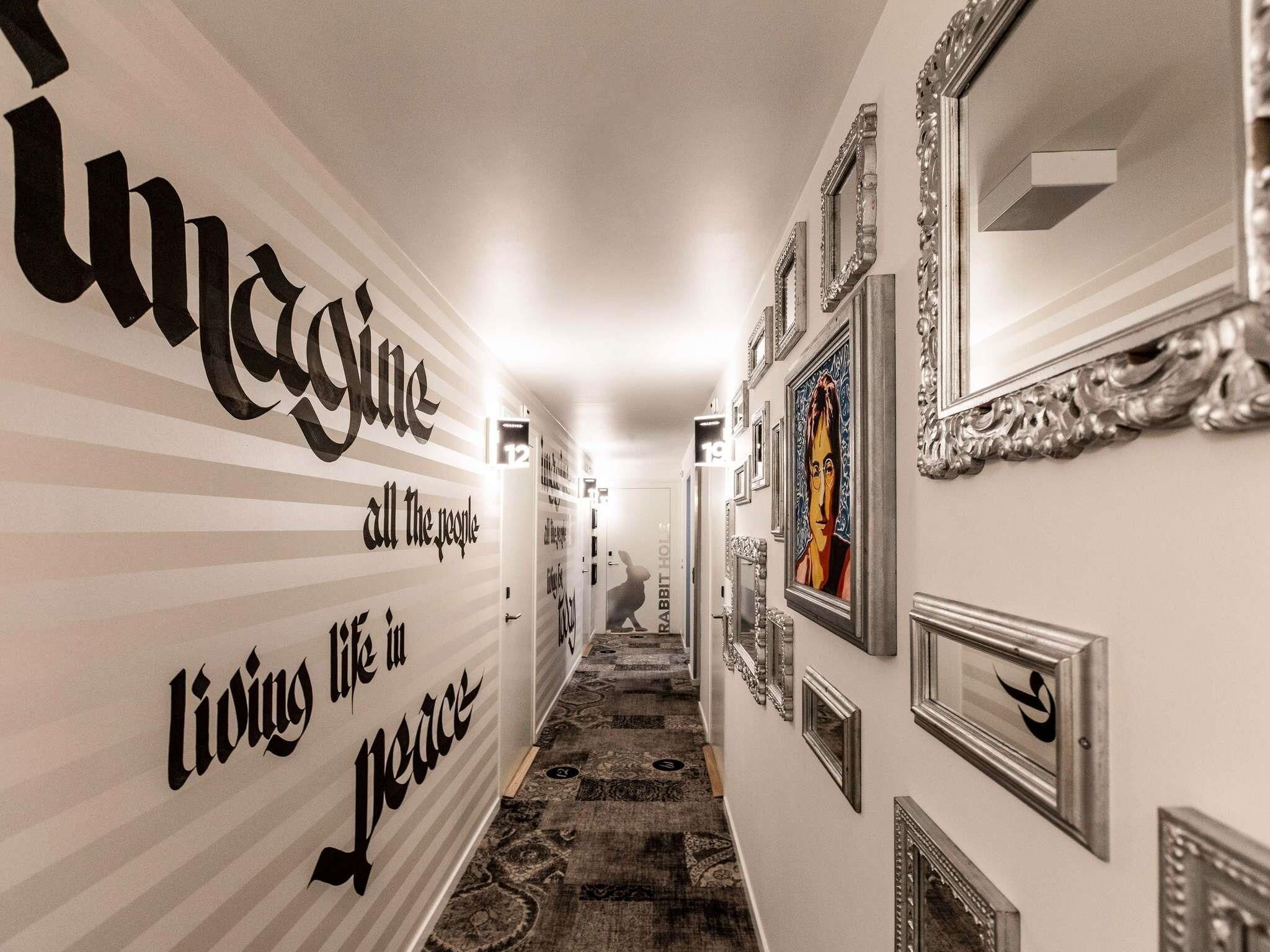 Un pasillo con pared a rayas, obras de arte enmarcadas y espejos ornamentados.
