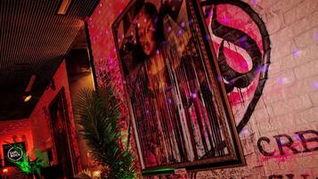 A dimly lit bar area with a graffiti wall, a framed picture, and a neon sign.