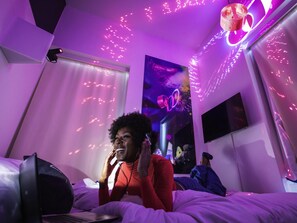 A bedroom with a bed, a wall-mounted TV, and a poster. - ibis Styles Lausanne Center Mad House (Lausanne)