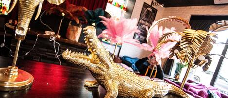 Una figurita de cocodrilo sobre una barra, una decoración de plumas y un letrero de neón en un bar.