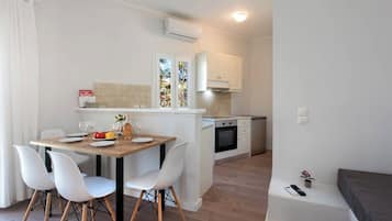 Una cocina pequeña con armarios blancos, una mesa de comedor de madera y sillas blancas.