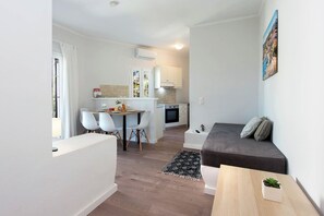 Un espace de vie compact comprenant une kitchenette, un coin repas et un coin salon.