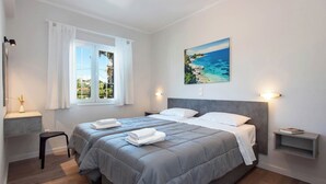 Un dormitorio con dos camas, una ventana con cortinas, un cuadro en la pared y lámparas de noche.