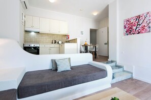 Un appartement moderne comprenant un canapé, une cuisine, un coin repas et un escalier.