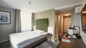 Habitación de hotel con cama, escritorio, silla, teléfono y un cuadro en la pared.