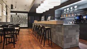 Zona de bar moderna con mostrador estampado, taburetes y una exhibición de vinos.