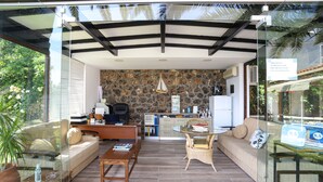 Uma sala de estar moderna com uma parede de pedra, uma mesa de centro de vidro, um sofá e uma mesa de jantar.