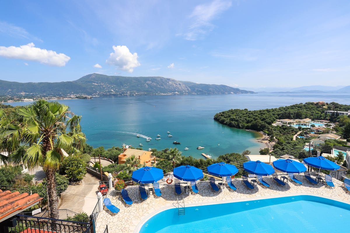 Un resort con piscina, sillas de descanso y sombrillas.