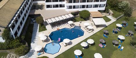 A large building with a swimming pool, multiple lounge areas, and outdoor seating.
