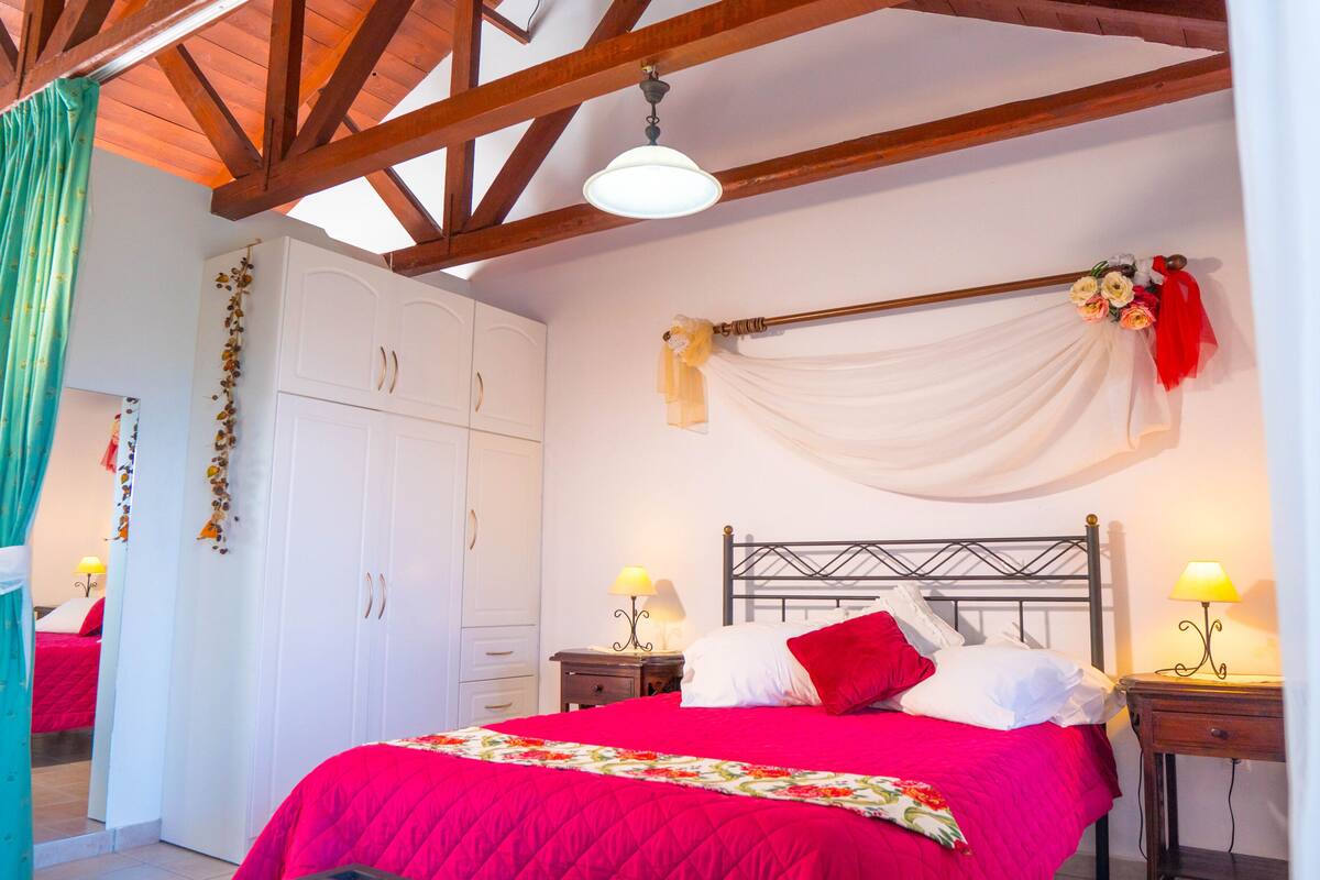 Un dormitorio con cama, armario blanco y dos mesitas de noche con lámparas.