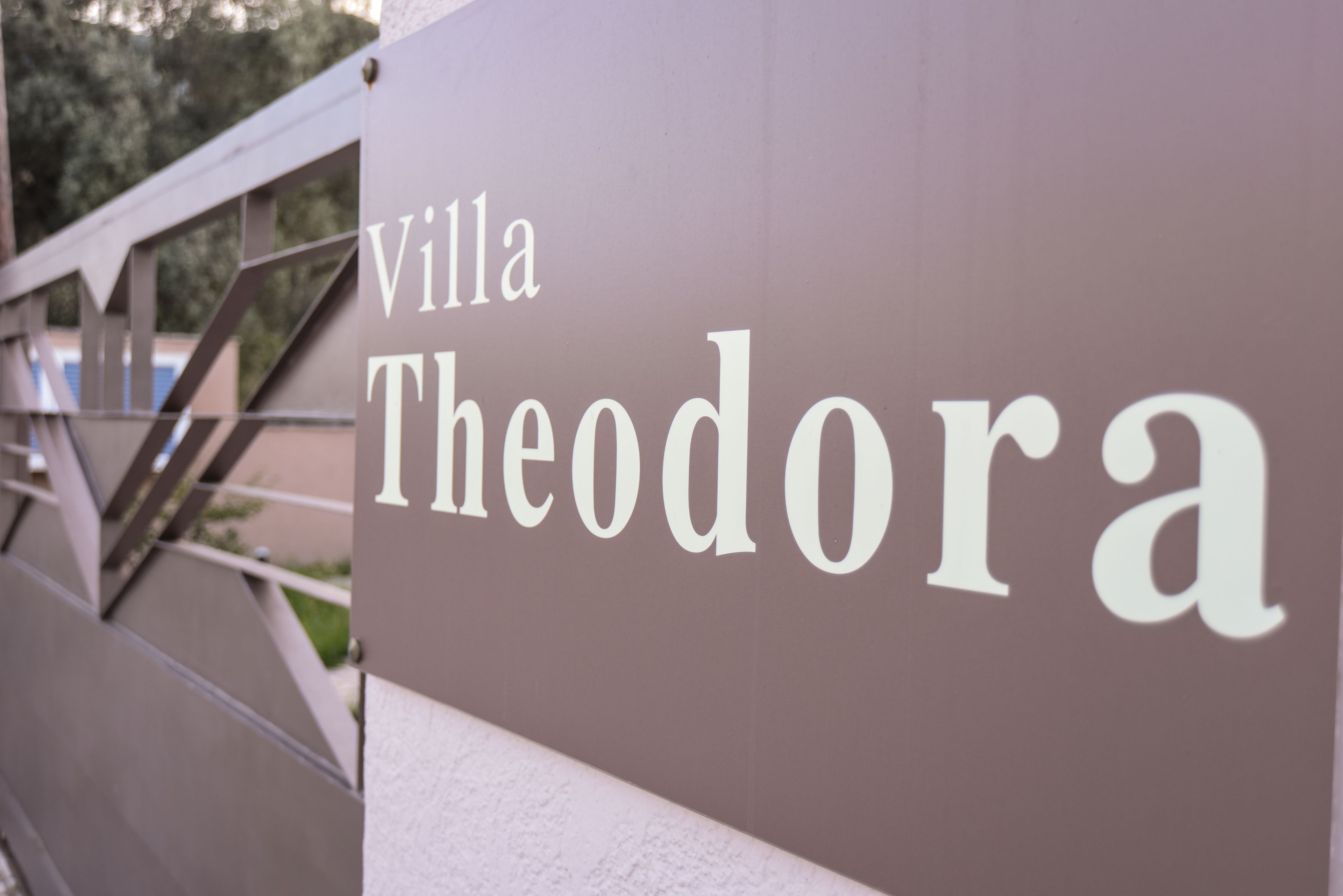 A sign with the text "Villa Theodora" on a building.