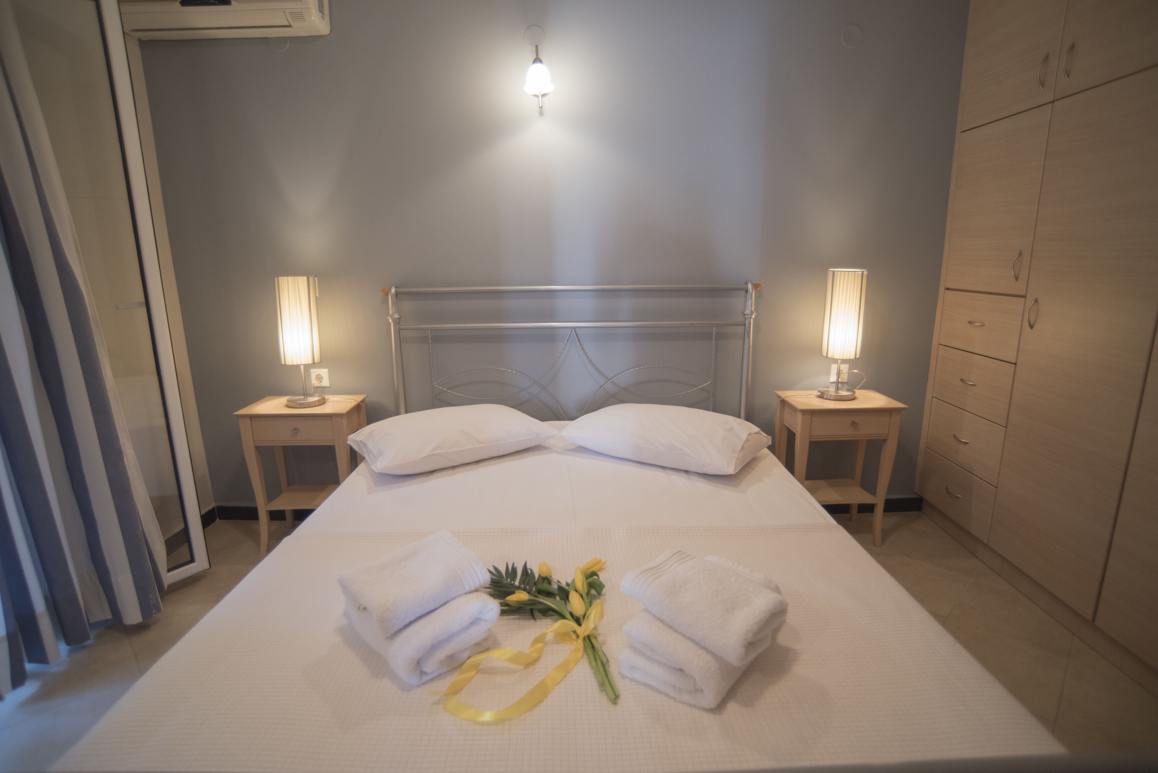 A neatly made bed with white linens, two bedside lamps, and a bouquet of flowers on the bed.
