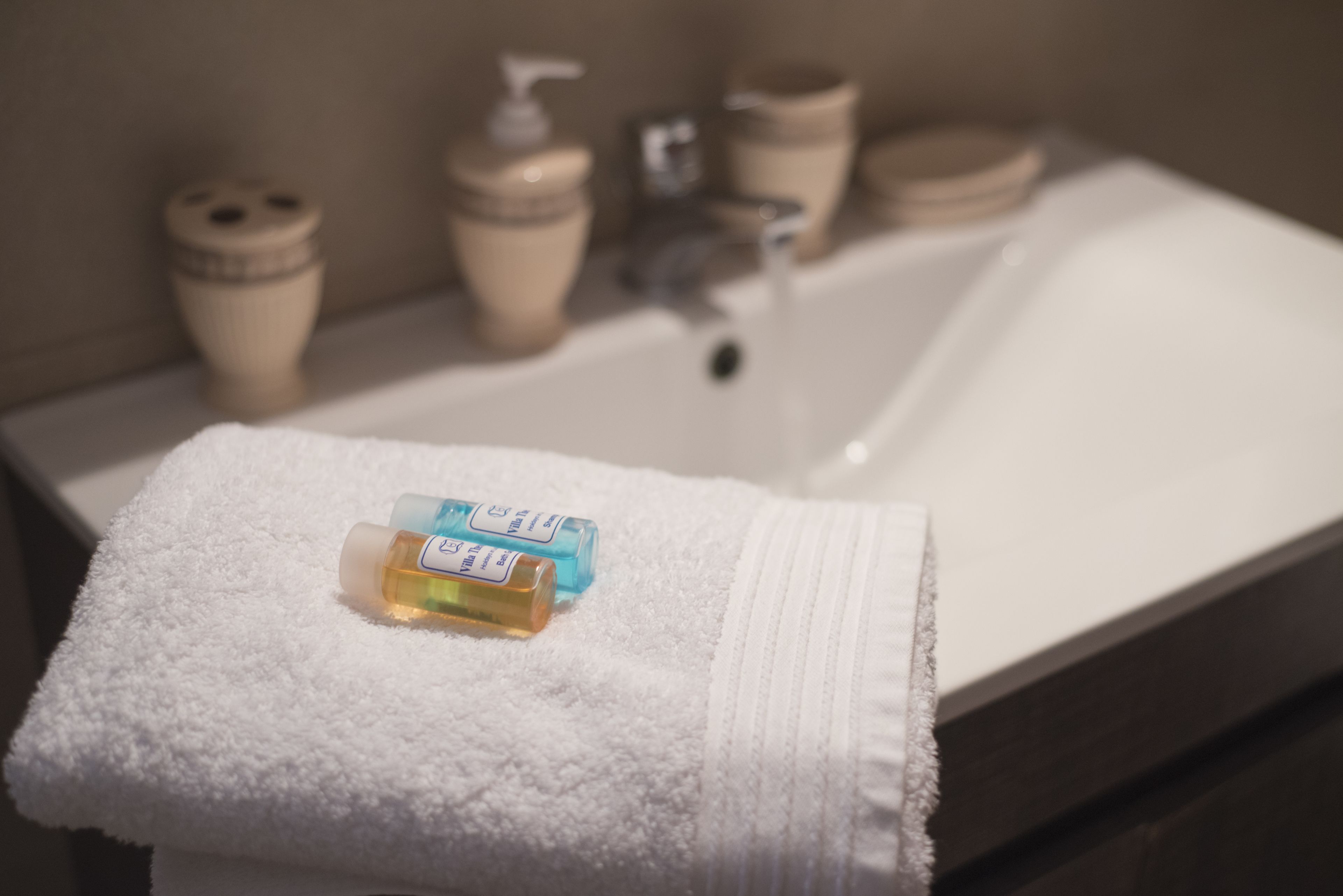 A bathroom with a white sink, a towel, and two bottles of lotion on the towel.