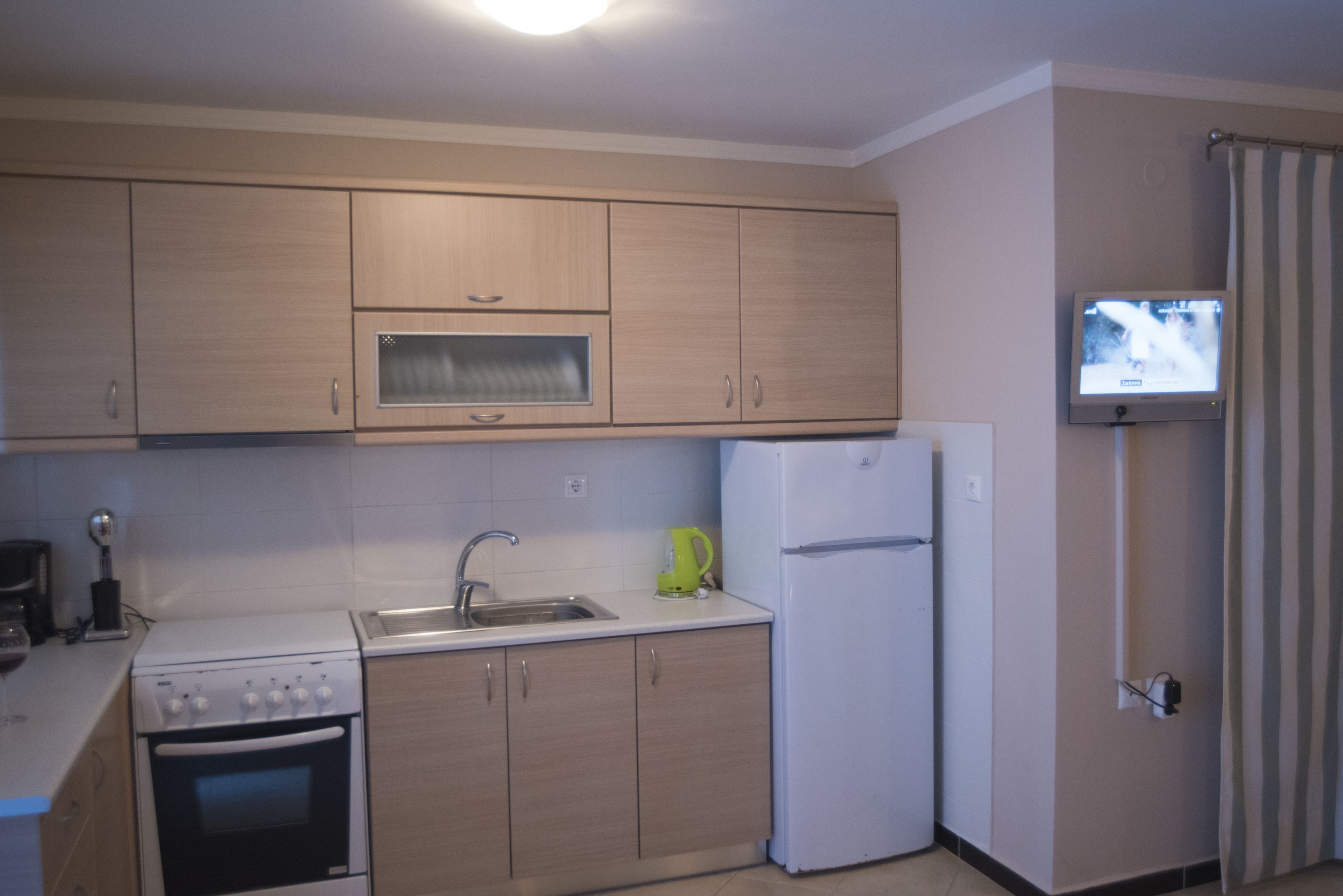 A compact kitchen with wooden cabinets, a white stove, a sink, and a small refrigerator.