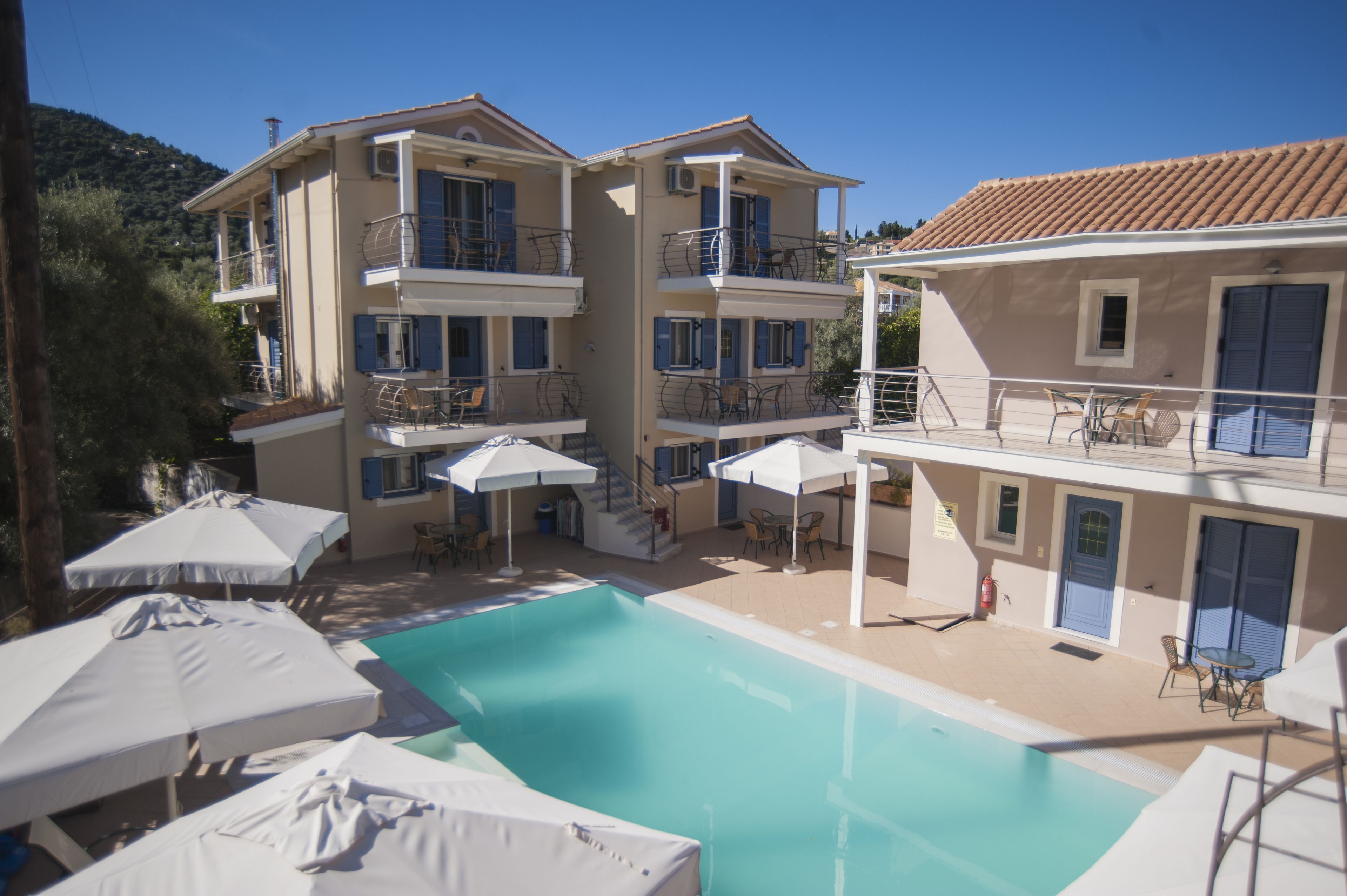 Un hotel con piscina, mobiliario exterior y varios balcones.