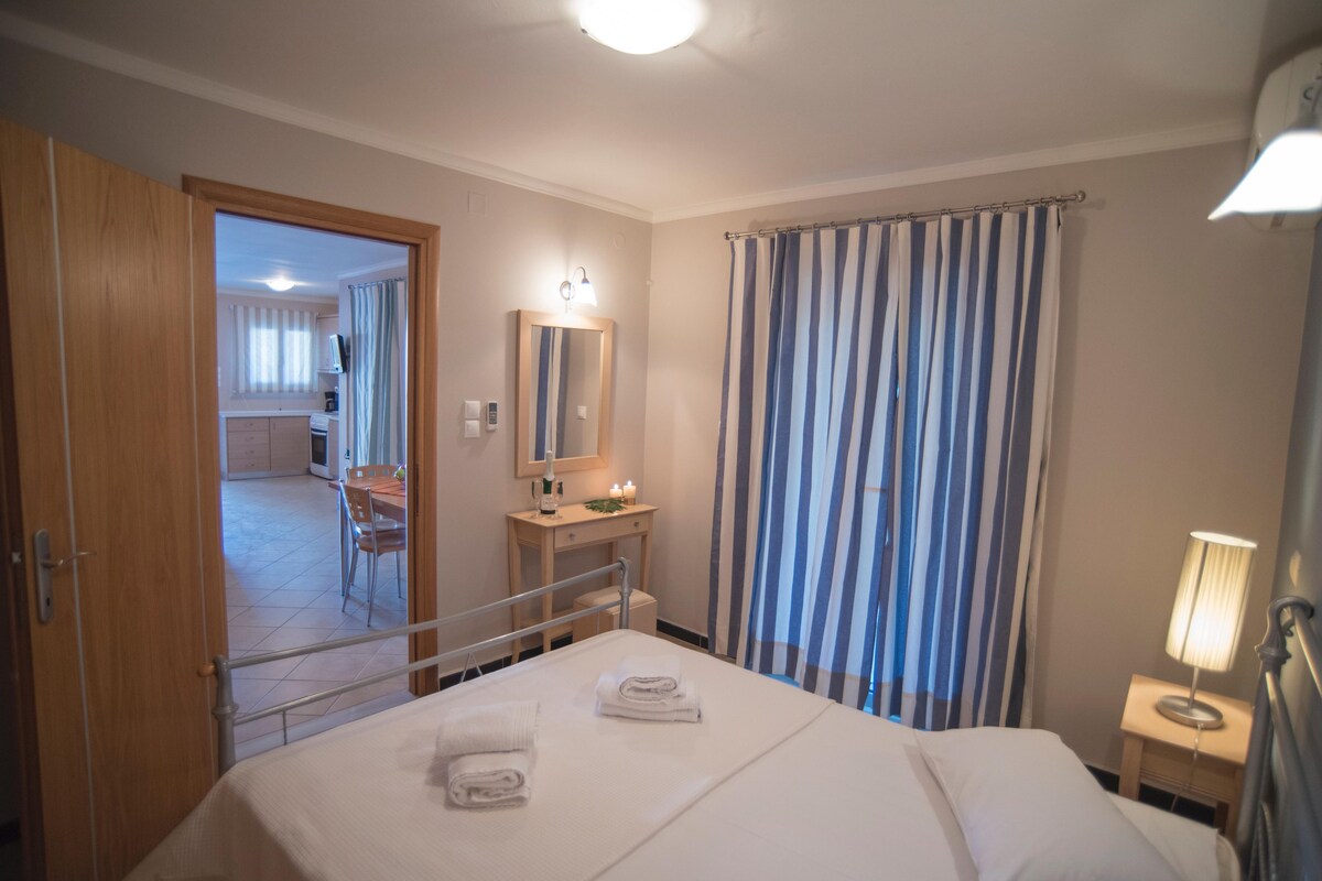 Une chambre d’hôtel avec un lit, une table de chevet avec une lampe, une salle de bain avec un rideau de douche et une vue sur la salle à manger.