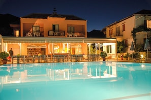 A hotel with a swimming pool, outdoor seating, and a bar area. - Athos Hotel (Lefkada)