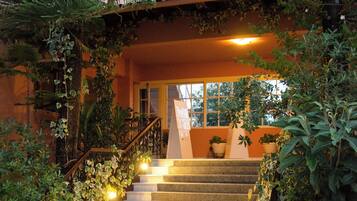 Una escalera conduce a la entrada de un edificio, rodeada de vegetación y escalones de piedra.