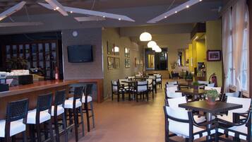 A restaurant with a bar area, multiple dining tables, and chairs.