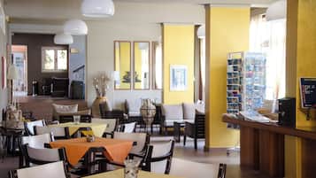 Un restaurante con varias mesas y sillas, una zona de bar y obras de arte enmarcadas en las paredes.
