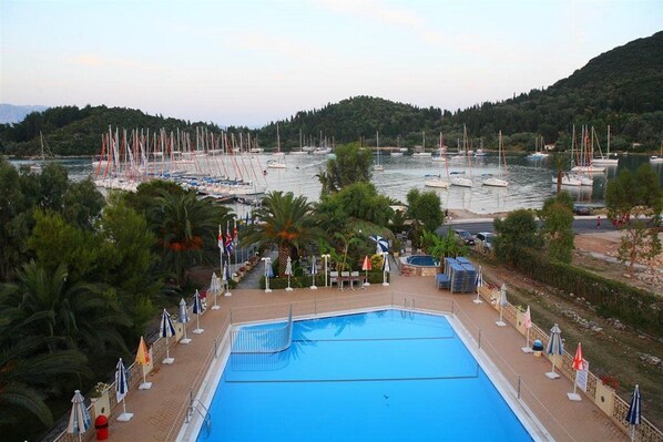 A swimming pool with a view of boats and hills in the background. - Athos Hotel (Lefkada)