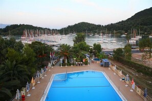 A swimming pool with a view of boats and hills in the background. - Athos Hotel (Lefkada)