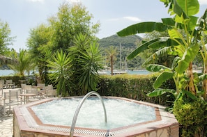 A hot tub surrounded by lush greenery and a view of the sea. - Athos Hotel (Lefkada)