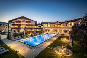 A large building with multiple balconies, a swimming pool, and outdoor seating areas. - Hotel Grünauerhof (Wals-Siezenheim)
