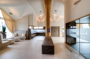 Un vestíbulo moderno de hotel con una zona de estar central, una sauna y una recepción.
