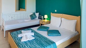 Un dormitorio con una cama, una cama adicional, una mesita de noche con lámpara y un espejo en la pared.