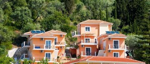 Un edificio de varios pisos con paredes anaranjadas y tejados rojos, que cuenta con balcones y paneles solares.