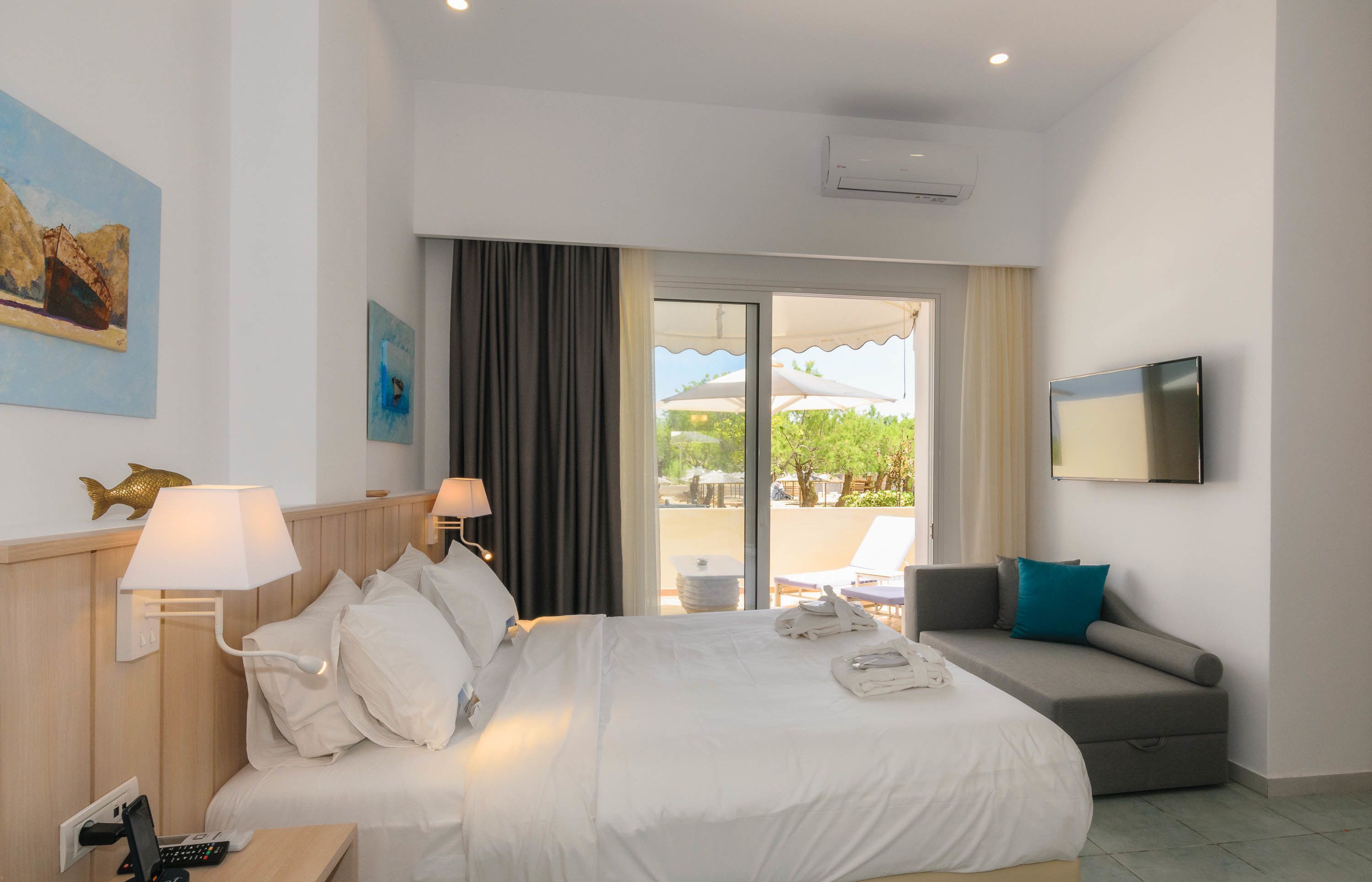 Habitación de hotel con cama, sofá, televisión y vistas al exterior.