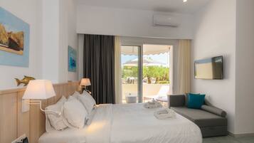 Habitación de hotel con cama, sofá, televisión y vistas al exterior.